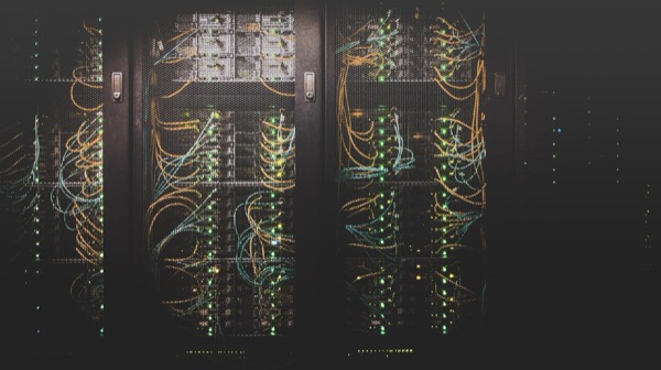 Two server racks filled with dense bundles of colored network cabling