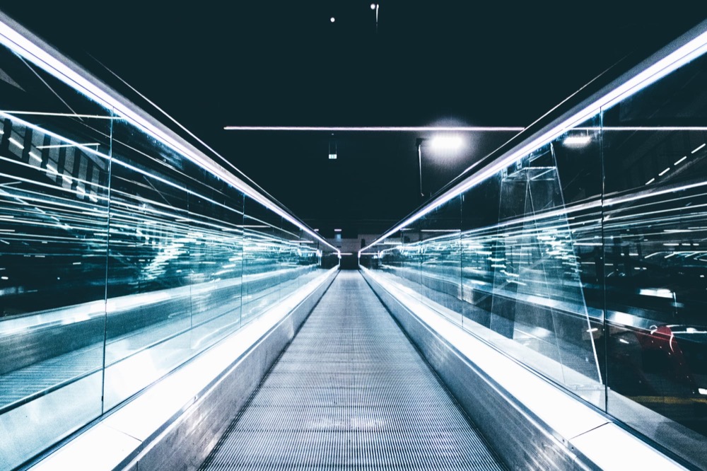 A moving walkway stretching into the distance, its handrails blurred by a long exposure
