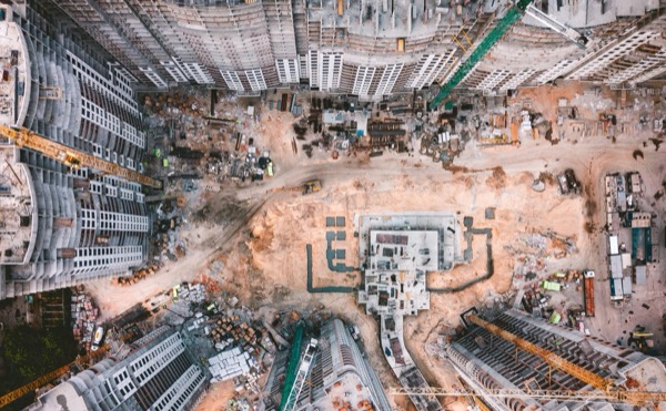 An aerial view of a large construction site, with cranes standing around exposed foundations