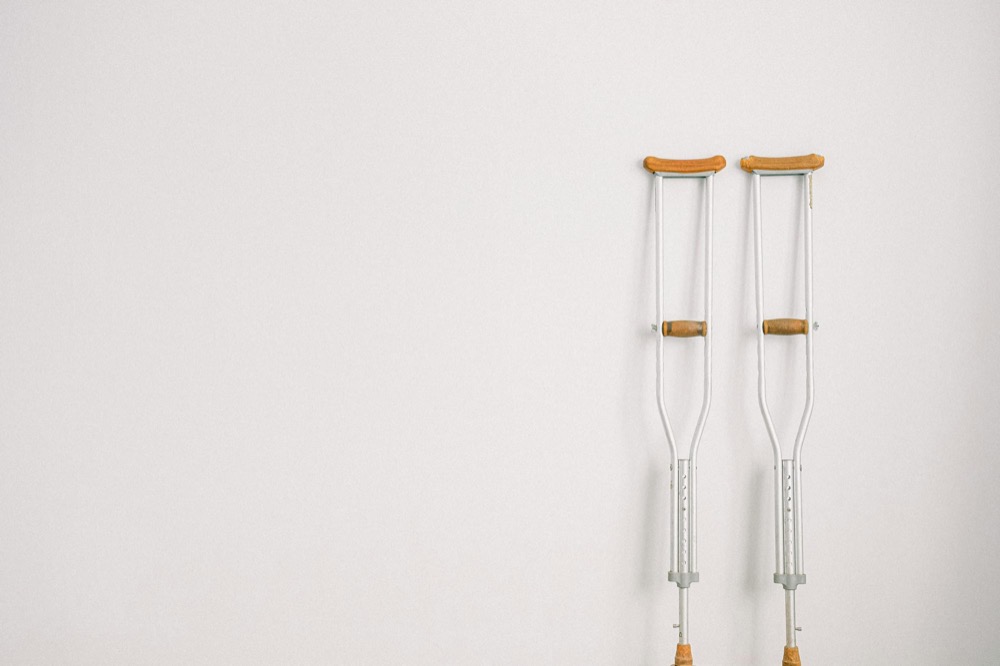 A pair of crutches leaning against a plain white wall