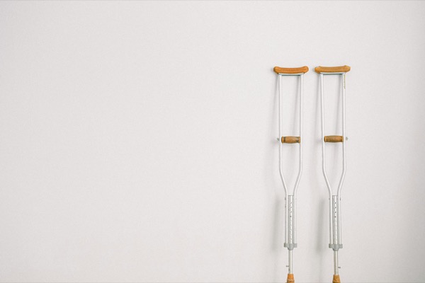 A pair of crutches leaning against a plain white wall