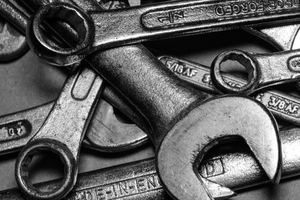 A pile of overlapping steel wrenches, in black and white