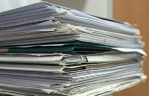 A tall, untidy stack of paper documents