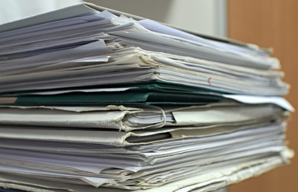 A tall, untidy stack of paper documents