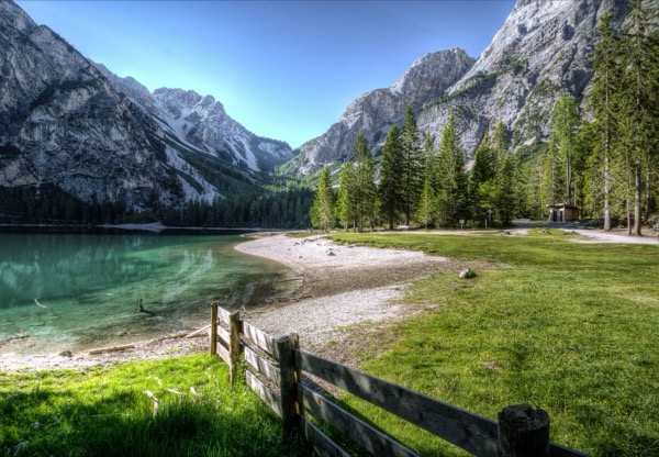 Turquoise alpine lake below limestone peaks, with a wooden fence in the foreground